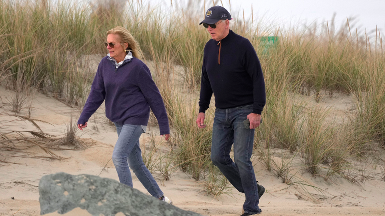 Biden seems to struggle while strolling on the beach with his wife.