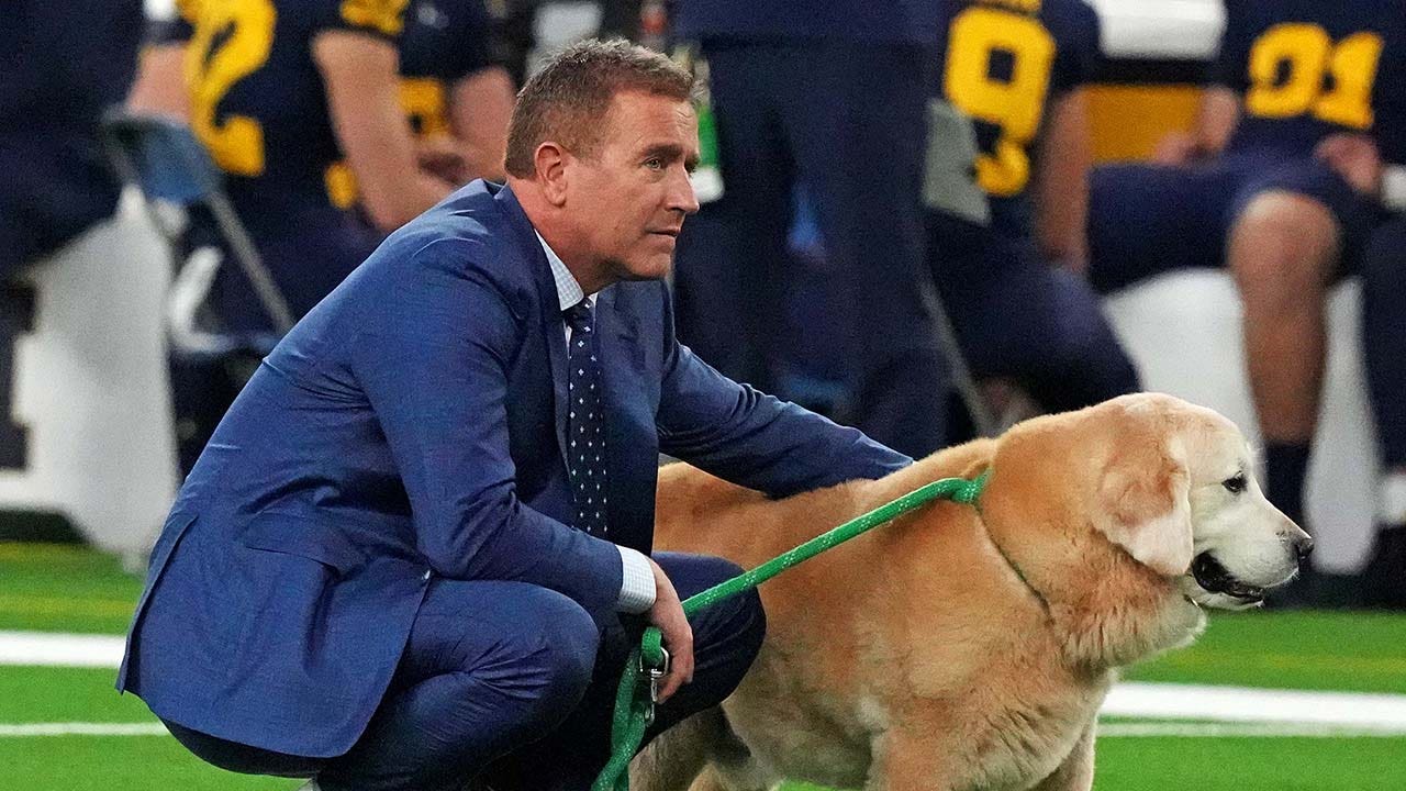 Kirk Herbstreit's dog Ben receives affection from Al Michaels despite criticism about his presence in the booth.