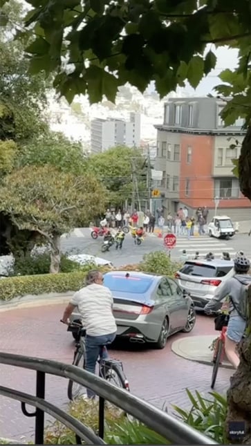 Masked motorcyclists surround San Francisco traffic officer in tourist district.