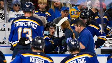 Blues player sustains neck injury from puck but continues playing until stretchered off.