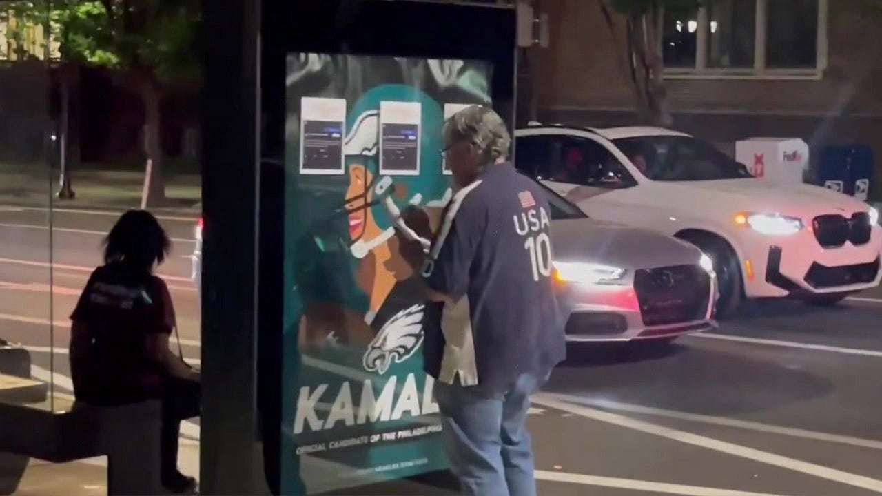 Eagles fan takes action to conceal fake political advertisements supporting Kamala Harris.